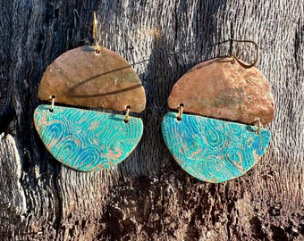 May include: A pair of dangle earrings featuring two stacked semi-circular components. The top half is a plain, weathered copper piece, while the bottom half is a turquoise-colored metal with a raised, swirling, embossed pattern.