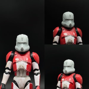 Può includere: Due action figure che indossano un'armatura rossa e bianca con elmetti grigi. Le figure sono in posizione eretta.