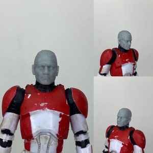 May include: A gray plastic action figure head with a sculpted face and short hair. The head is attached to a red and white plastic body with black accents. The figure is wearing a red and white armor with black details.