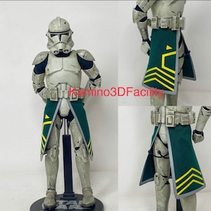 May include: A white and gray Star Wars action figure of a clone trooper with a green and yellow cape. The figure is wearing a helmet and has a blaster rifle.