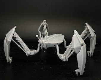 Könnte beinhalten: Ein graues, artikuliertes, mehrbeiniges Roboter-Spielzeug mit einem zentralen Körper und mehreren Gelenkbeinen. Der Roboter ist in einer stehenden Position mit gespreizten Beinen aufgestellt.