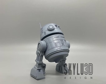 May include: A gray 3D printed model of a robot with a round body and two legs. The robot has a detailed design with various panels and buttons. The model is standing on a gray surface. The text "SKYLU3D DESIGN" is visible in the lower right corner of the image.