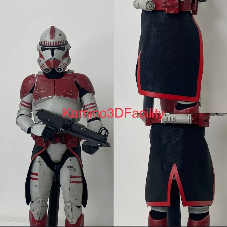 May include: A red and white Star Wars clone trooper action figure with a black blaster rifle. The figure is wearing red and white armour with a black cape. The figure is standing on a white background.