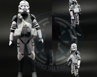 May include: A white and gray action figure of a Star Wars clone trooper. The figure is wearing a white helmet with a black visor, a white and gray armor, and a black and gray backpack. The figure is standing on a black surface.