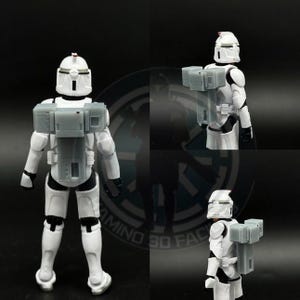May include: Two white action figures of Star Wars clone troopers with backpacks. The figures are posed standing with their arms at their sides. The figures are wearing white armor with gray accents. The figures are holding weapons in their hands.