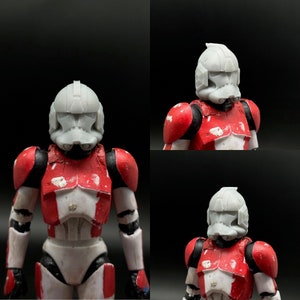 May include: A white plastic clone trooper helmet with red and white armour. The helmet has a visor and a detailed design.