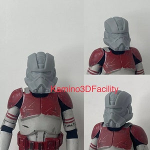 Puede incluir: Un casco de plástico gris con un diseño detallado, que se asemeja a un casco de soldado clon de Star Wars. El casco se muestra en una figura con armadura roja y blanca.