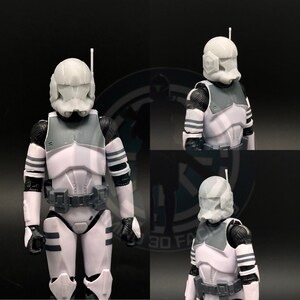 May include: A white plastic action figure helmet with a grey visor and a black antenna. The helmet is part of a Star Wars clone trooper action figure.