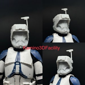 May include: A gray 3D-printed helmet, a replica of a Star Wars clone trooper helmet, is displayed in multiple views. The helmet features a distinctive visor and antenna. The figure is wearing a white and blue uniform. The text "Kamino3DFacility" is visible.