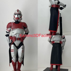 May include: A red and white Star Wars action figure of a clone trooper with a black cape. The figure is posed standing with its arms at its sides. The figure has a red and white helmet and a red and white chest plate. The figure is wearing a black cape with a red trim.