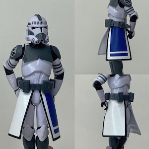 May include: A white and gray action figure of a Star Wars clone trooper wearing a white and blue cape. The figure has a detailed helmet and armor.
