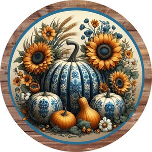 May include: A round wooden sign with a blue and white border. The center of the sign features a fall-themed design with three blue and white pumpkins, sunflowers, and other fall foliage.