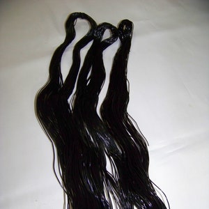 Puede incluir: Un paquete de cordón elástico negro, probablemente utilizado para la fabricación de joyas o manualidades.