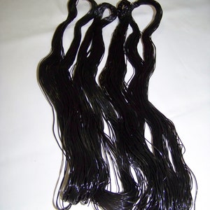 Puede incluir: Un paquete de cordón elástico negro, probablemente utilizado para la fabricación de joyas o manualidades.