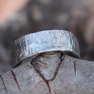 May include: A silver hammered band ring with a textured finish.