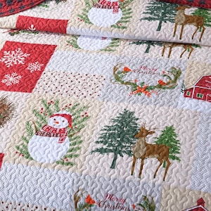 May include: A red and cream patchwork quilt with a Christmas theme. The quilt features snowmen, reindeer, pine trees, snowflakes, and a red barn with the text "Lucky snow winter happy holidays".