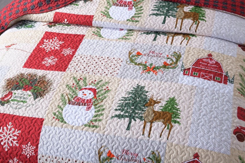 May include: A red and cream patchwork quilt with a Christmas theme. The quilt features snowmen, reindeer, pine trees, snowflakes, and a red barn with the text "Lucky snow winter happy holidays".