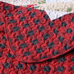 May include: Red and black plaid quilt with a quilted pattern of small circles. The quilt is folded over itself, showing the stitching detail.