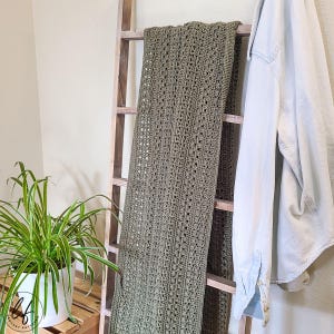 This image shows the crochet rectangle shawl draped over a blanket ladder.