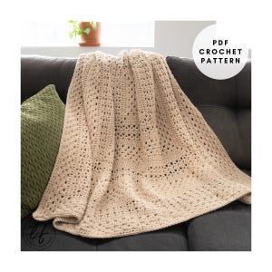 Puede incluir: Una manta beige de ganchillo con un diseño de tejido abierto, sobre un sofá gris oscuro. Un cojín verde es visible a la izquierda. El texto "PDF CROCHET PATTERN" está en un círculo blanco en la esquina superior derecha. La manta mide unos 150 cm x 200 cm.