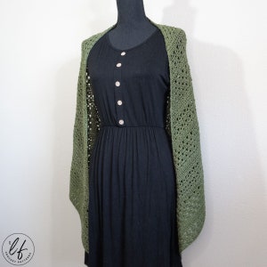 This image shows the crochet triangle shawl pattern sample draped over a mannequin as a woman would wear it. The crochet shawl is shown from the front, so the shawl is open and draped over the shoulders. The crochet wrap is made in olive green yarn.