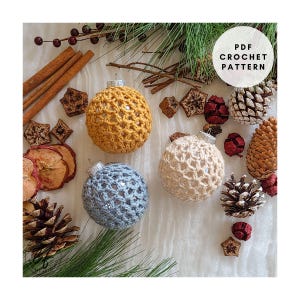 May include: A collection of handmade crochet Christmas ornaments in yellow, cream, and blue. The ornaments are displayed with pine cones, cinnamon sticks, and dried fruit. The image includes the text "PDF Crochet Pattern".