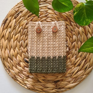 A crochet kindle case with a beige top and a green bottom.