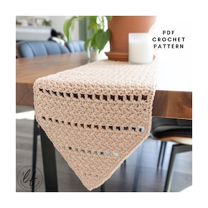 May include: A beige crochet table runner with a textured pattern and openwork design. The runner is displayed on a wooden table. The text "PDF CROCHET PATTERN" is visible in the upper right corner.