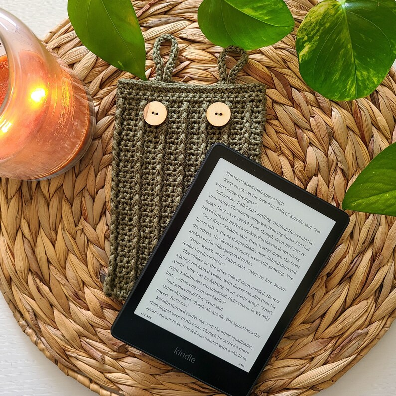 This image shows a kindle sitting on top of a green crochet kindle cover, made from this crochet kindle cover pattern.