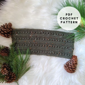 Puede incluir: Una diadema de ganchillo verde con motas marrones y blancas, rodeada de piñas y agujas de pino sobre una superficie blanca y esponjosa. El texto "PDF CROCHET PATTERN" está en un círculo blanco.