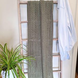 This image shows the crochet shawl pattern draped over a blanket ladder.
