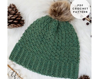 Peut inclure: Un bonnet vert crocheté avec un pompon en fausse fourrure. Le chapeau a un bord côtelé et un motif de point texturé. L'image comprend le texte "PDF Crochet Pattern".