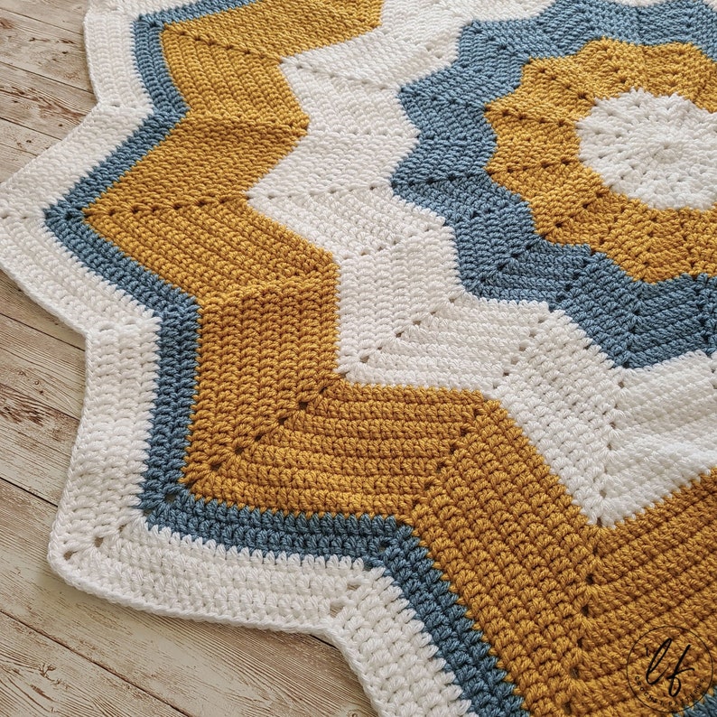 A crochet star baby blanket with a white, blue, and mustard yellow color scheme.