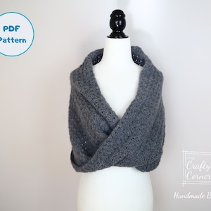 May include: A gray crochet shawl with a cowl neck, displayed on a white mannequin. The shawl is made with a simple stitch pattern and has a relaxed, drapey fit. The text "Crafty Corner Handmade By Mei" is visible in the lower right corner of the image.