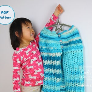 Könnte beinhalten: Ein blaues und weißes Häkel-Cardigan, das an einem sternförmigen Kleiderbügel hängt. Das Cardigan hat einen Knopfverschluss und einen gewellten Saum. Der Text "Crafty Corner Handmade By Mei" ist in der rechten unteren Ecke des Bildes zu sehen.