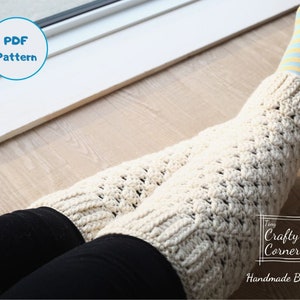 Puede incluir: Un par de polainas blancas de ganchillo con un patrón texturizado. Las polainas se llevan sobre pantalones negros y calcetines a rayas azules y amarillas. El texto "Tiny Crafty Corner Handmade By Mei" es visible en la esquina inferior derecha de la imagen.