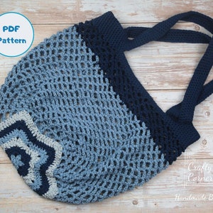 May include: A crocheted blue and white mesh bag with a star design at the bottom and navy blue handles. The bag is on a wooden surface. PDF Pattern.