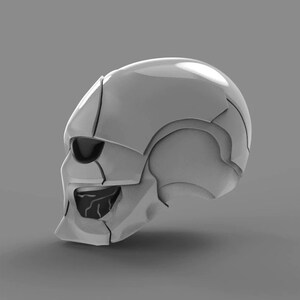 May include: A white, futuristic-looking skull helmet with a detailed design. The helmet has a single eye opening and a segmented, textured surface.