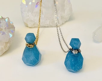 May include: Two blue crystal bottle necklaces with gold and silver chains. The necklaces are displayed on white crystal clusters.
