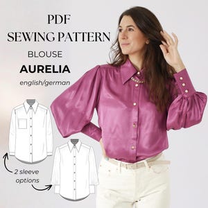 May include: A woman wearing a magenta blouse with puffed sleeves and gold buttons. The blouse is paired with white pants and a light-colored belt. The image also features a PDF sewing pattern for a blouse named "Aurelia" with two sleeve options.