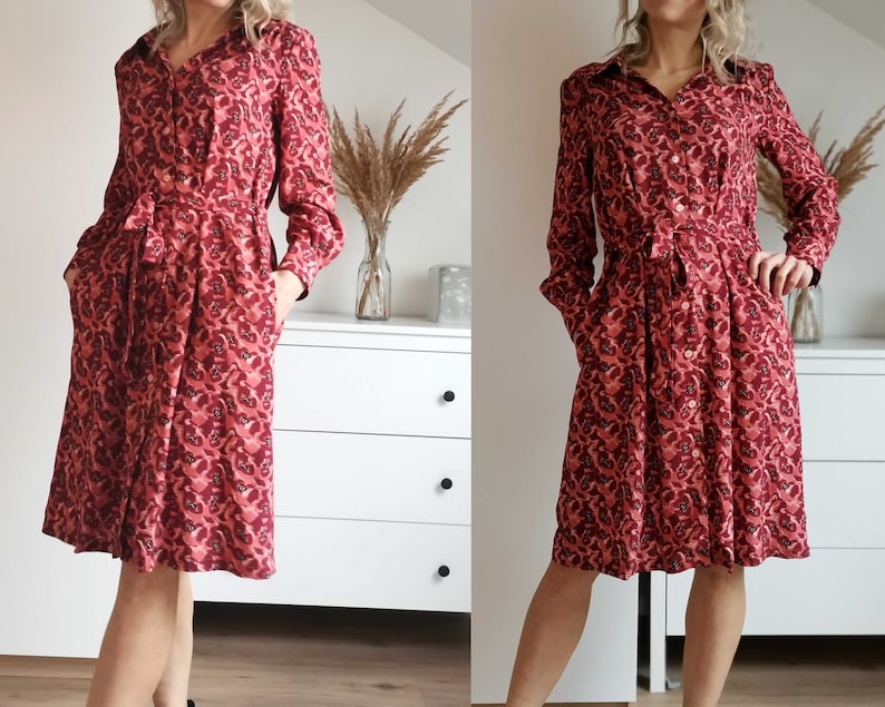 May include: A red and pink patterned long-sleeved dress with a button-up front and a tie belt.