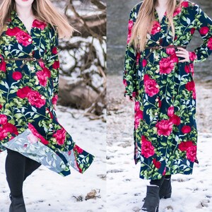May include: A long-sleeved floral dress with a button-up front and a belt. The dress has a dark blue background with large red and pink flowers. The model is wearing the dress with black leggings and black boots.