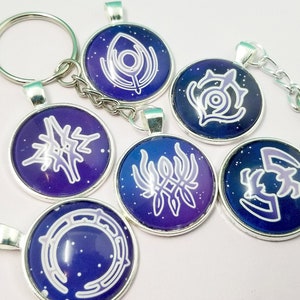 May include: Six silver keychains with round, blue and purple glass charms featuring white symbols. Each charm has a different symbol.