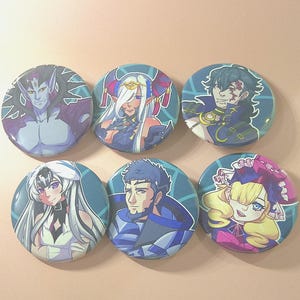 May include: Six round buttons with colorful anime-style character illustrations. The buttons feature various characters with detailed designs, including a purple-skinned figure, a woman with white hair, and a man with a scar.