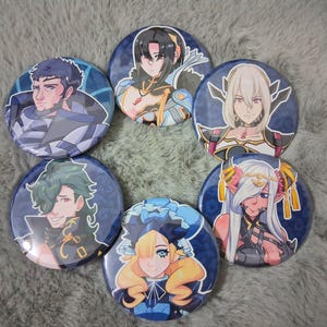 May include: A collection of seven round, blue and white character art buttons. Each button features a different anime-style character portrait. The characters have various hair colors and wear detailed outfits. The buttons are arranged in a circular pattern.
