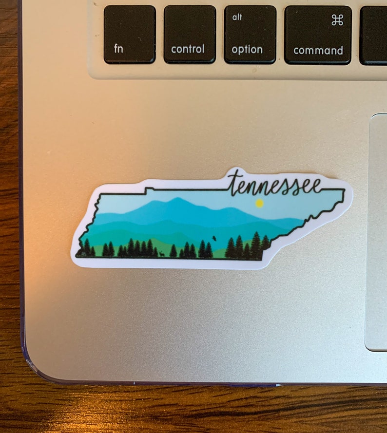 May include: A sticker of the state of Tennessee with a blue and green mountain landscape and the word "Tennessee" written in cursive.
