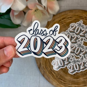 May include: A white sticker with the text "Class of 2023" in a rainbow color scheme. The numbers are in a 3D style with a shadow effect.