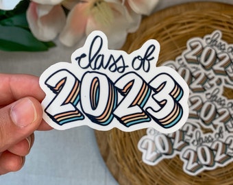 May include: A white sticker with the text "Class of 2023" in a rainbow color scheme. The numbers are in a 3D style with a shadow effect.