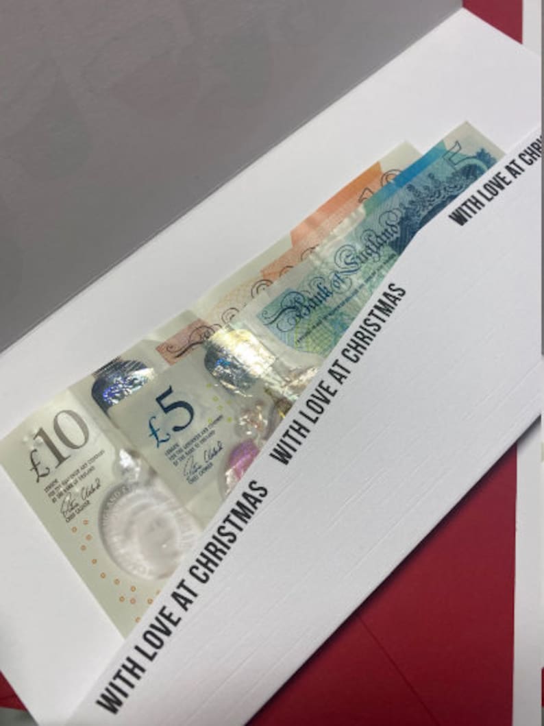 May include: A white envelope with a red border. The envelope is open and contains several British pound notes. The text "WITH LOVE AT CHRISTMAS" is printed on the envelope.