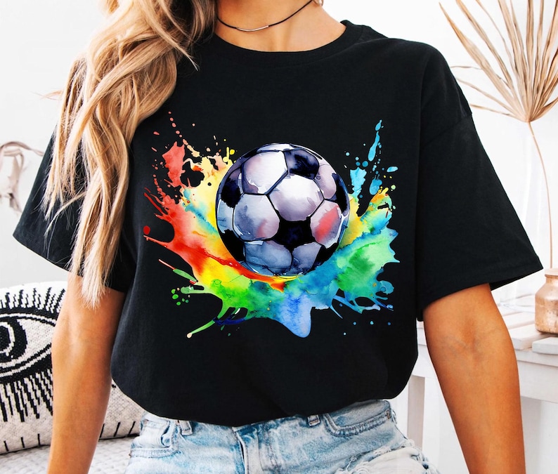 K&ouml;nnte beinhalten: Schwarzes T-Shirt mit einem farbenfrohen Aquarell-Design eines Fu&szlig;balls. Das Design enth&auml;lt Spritzer in Gelb, Orange, Rot, Gr&uuml;n, Blau und Lila.